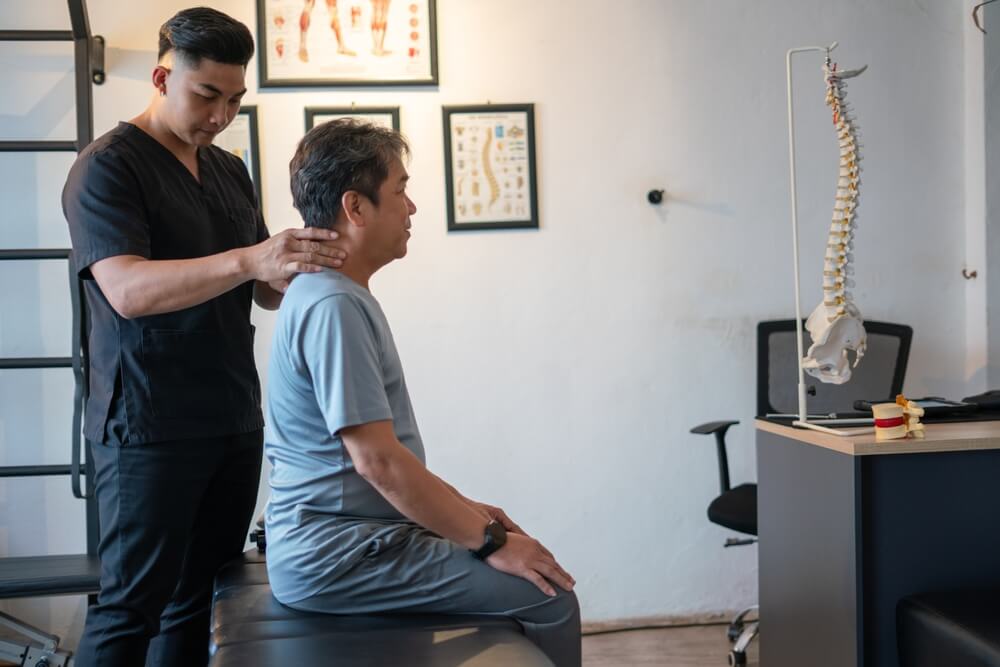 Chiropractic Assistant checking a patient and aligning his posture