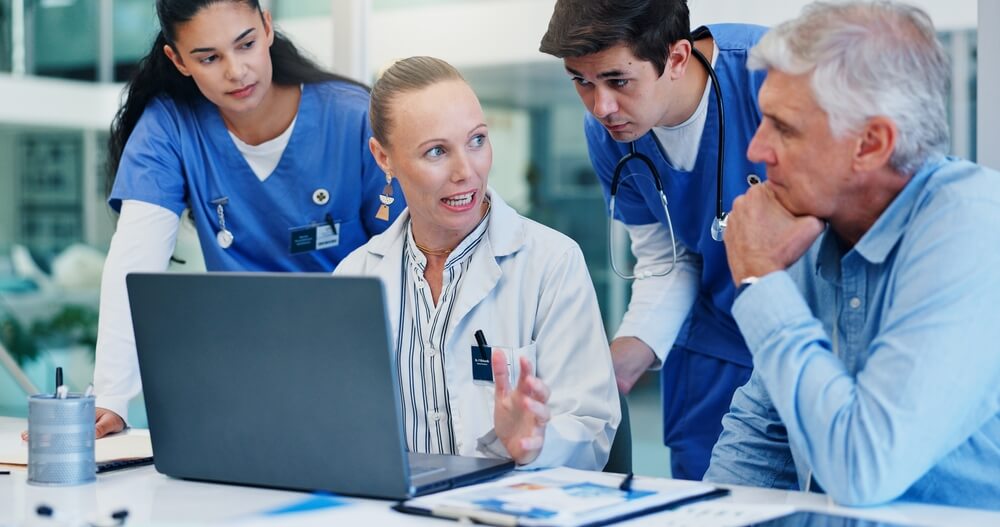 in-person medical scribe documenting patient visit beside physician in clinic exam room