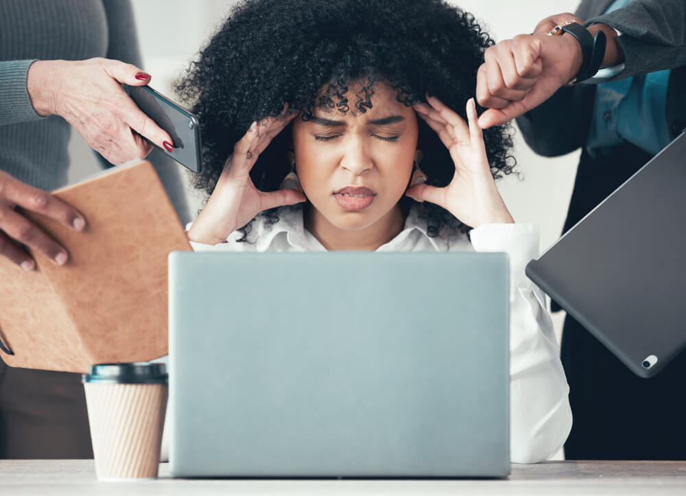 Exhausted remote employee sitting at laptop with tired expression and low energy
